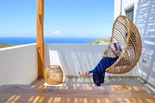 a woman sitting in a hanging chair reading a book at Milos Zen Suites in Adamas