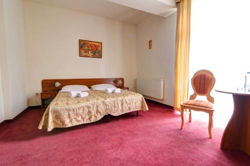 a bedroom with a bed with two pillows and a chair at Apartamenty Renesans in Krynica Zdrój