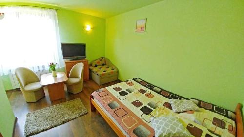 a green room with a bed and a television at Pensjonat Koral in Darłówko