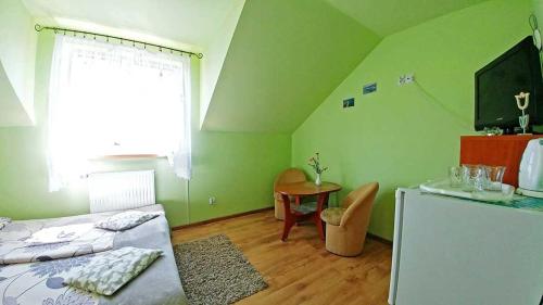 a green room with a bed and a table at Pensjonat Koral in Darłówko