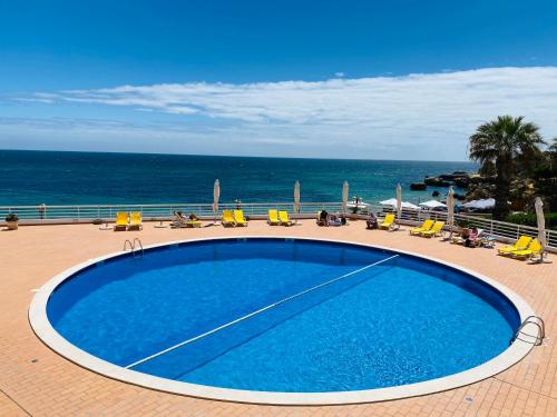 a swimming pool with chairs and the ocean in the background at Borda d`Água, Praia da Oura in Albufeira