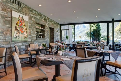 a restaurant with tables and chairs and a stone wall at Romantik Hotel Castello Seeschloss in Ascona