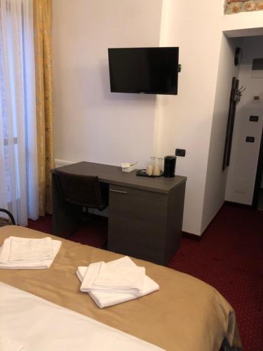 a hotel room with a desk and a tv on the wall at Pensiunea SADA in Făgăraş