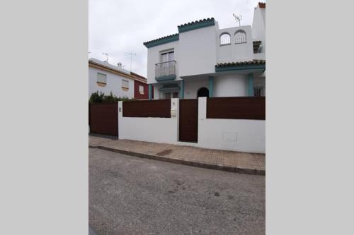 ein weißes Haus mit einem Zaun an einer Straße in der Unterkunft CASA DE DISEÑO EN LA PLAYA. in Rota