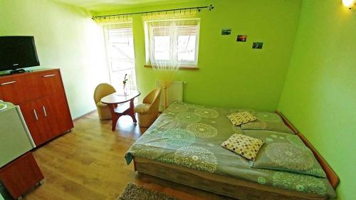 a green bedroom with a bed and a table at Pensjonat Koral in Darłówko
