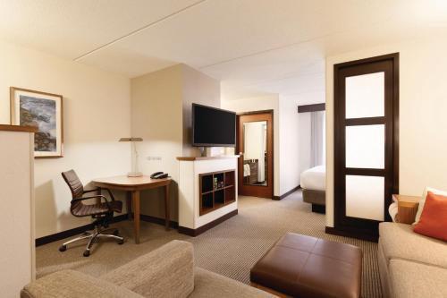 a living room with a couch and a desk with a television at Hyatt Place Chicago - Lombard/Oak Brook in Lombard