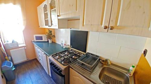 a kitchen with a stove top oven next to a sink at Pensjonat Koral in Darlowko