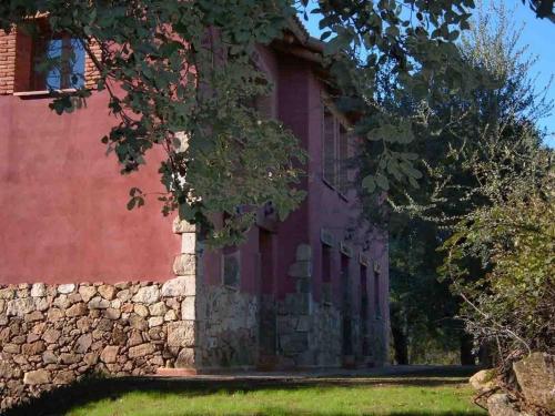 un edificio antiguo con una pared de piedra y árboles en Apartamentos Rurales La Oropendola, en Jaraíz de la Vera