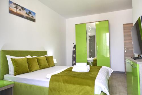 una camera da letto verde e bianca con un letto e una televisione di Green Apartment Spa n Pool Beach Resort a Mamaia Nord - Năvodari