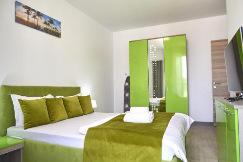 ein grün-weißes Schlafzimmer mit einem Bett und einem TV in der Unterkunft Green Apartment Spa n Pool Beach Resort in Mamaia Nord – Năvodari