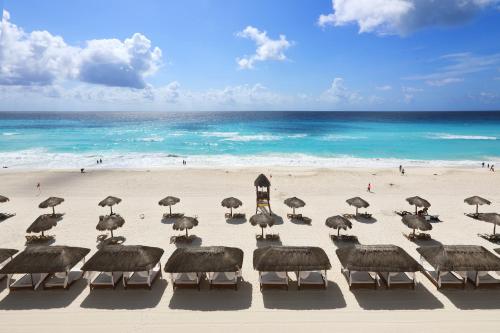a group of umbrellas on a beach with the ocean at Emporio Cancun - Buy All Inclusive Option in Cancún