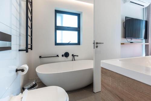a white bathroom with a tub and a sink at Latitude Aparthotel by Totalstay in Cape Town