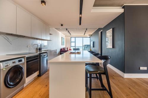 a kitchen with a counter and a washer and dryer at Latitude Aparthotel by Totalstay in Cape Town