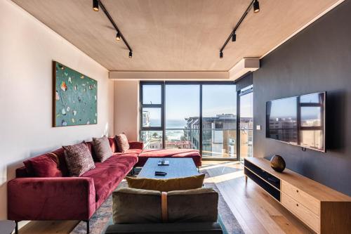 sala de estar con sofá rojo y ventana grande en Latitude Aparthotel by Totalstay en Ciudad del Cabo