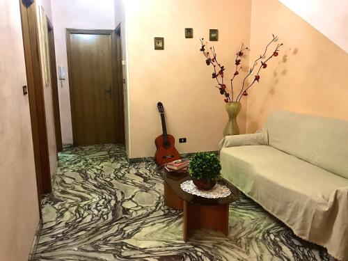 ein Wohnzimmer mit einem Sofa und einer Gitarre auf dem Boden in der Unterkunft Regina di denari in Pachino
