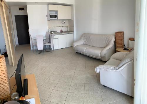 a living room with couches and a table and a kitchen at Apartament Safir Mamaia in Mamaia