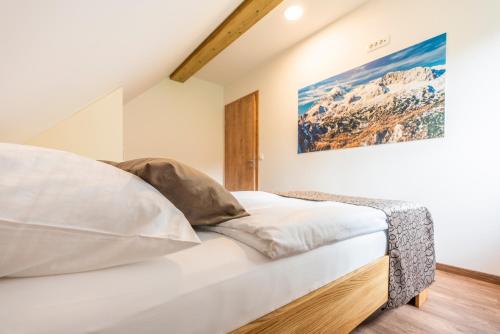 a bed in a room with a painting on the wall at Apartmaji MM in Bohinj