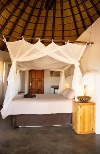 a bedroom with a large white bed with a canopy at Lamai Safari Lodge in Balule Game Reserve
