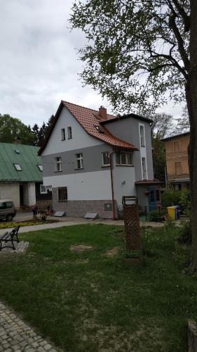 una gran casa blanca con un árbol delante en Pawi Ogon, en Sokołowsko