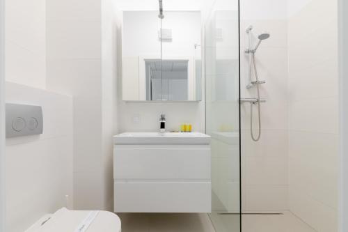 a white bathroom with a sink and a shower at Wola Chic Studios in Warsaw