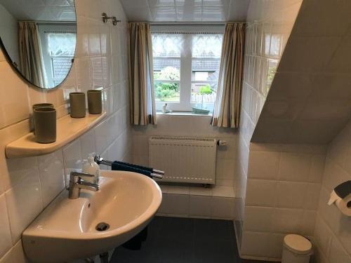 baño con lavabo, espejo y ventana en Haus-Dorfstrasse, en Risum-Lindholm