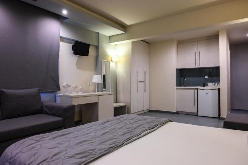 a bedroom with a bed and a chair and a kitchen at Blue Sea Boutique Apartments in Olympiaki Akti