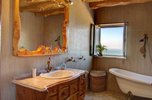 a bathroom with a sink and a tub and a mirror at Rancho Mar à Vista in Atalaia de Cima