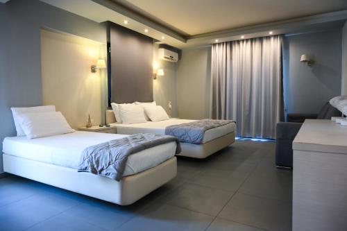 a hotel room with two beds and a couch at Blue Sea Boutique Apartments in Olympiaki Akti