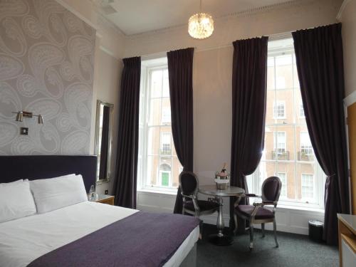 a hotel room with a bed and a table and windows at Jackson Court Hotel in Dublin