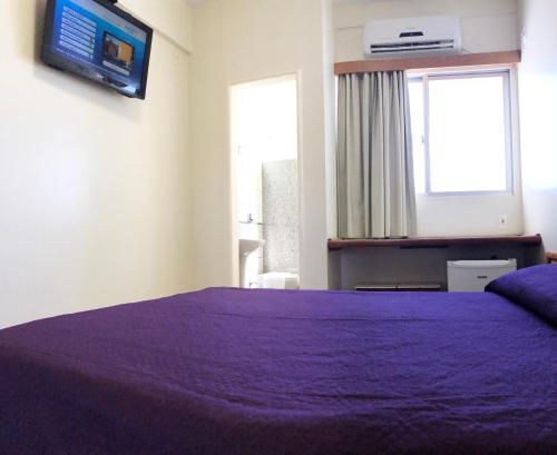 a bedroom with a bed and a television at Hotel Serra das Águas in Goiânia