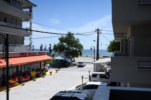 a street with cars parked in a parking lot next to the ocean at Blue Sea Boutique Apartments in Olympiaki Akti