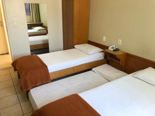 a room with two beds and a mirror at Hotel Serra das Águas in Goiânia