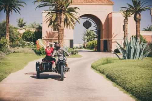 a man and woman riding a motorcycle down a road at Fairmont Royal Palm Marrakech in Marrakech