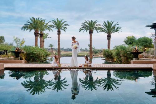 a bride standing in front of a swimming pool with palm trees at Fairmont Royal Palm Marrakech in Marrakech