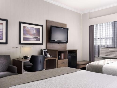 a hotel room with a bed and a desk and a television at BEST WESTERN PLUS Carlton Plaza Hotel in Victoria
