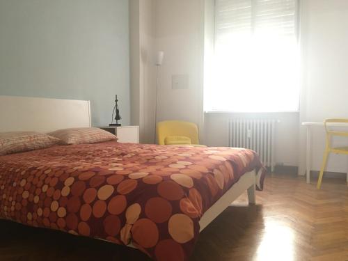 a bedroom with a bed with a orange comforter and a window at R&B Errepì Piola in Milan