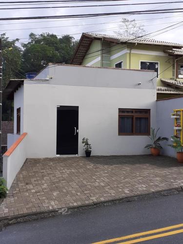 a white house with a black door on a street at loft harmonia in Blumenau