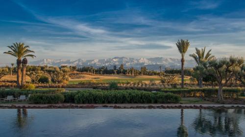 a golf course with palm trees and water and mountains at Fairmont Royal Palm Marrakech in Marrakech