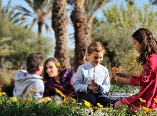 a group of children sitting in the grass with flowers at Fairmont Royal Palm Marrakech in Marrakech