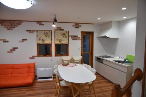 a kitchen with an orange couch and a white table at Kawaguchiko Cottage Minami in Fujikawaguchiko