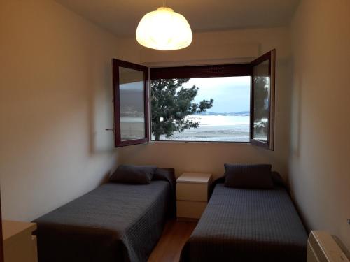 um quarto com 2 camas e uma janela em Apartamento Playa de Boiro em Boiro