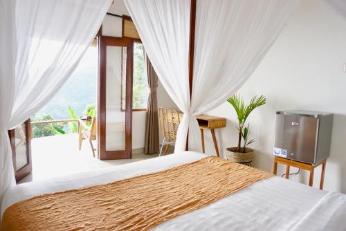 a bedroom with a bed and a balcony at Aryautama Garden Villa in Munduk