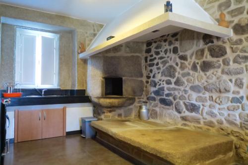 a kitchen with a stone wall with a stove at Casa do Rei in Boiro