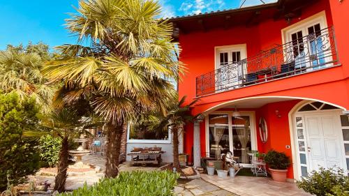 a red house with palm trees in front of it at B&B Villa Botto in Cossato