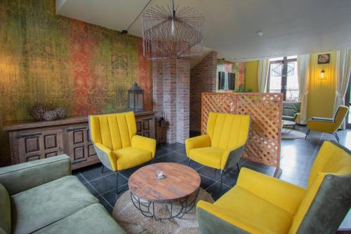 a living room with yellow chairs and a table at Hotel des Comtes Durbuy in Durbuy