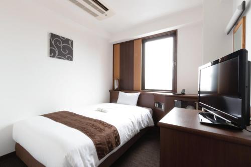 a hotel room with a bed and a flat screen tv at Toyo Hotel in Fukuoka