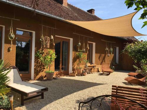 a patio with chairs and a table and a building at Massages du Monde in Saint-Georges-sur-la-Prée