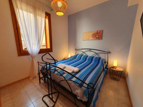 sypialnia z łóżkiem z niebieską pościelą i oknem w obiekcie Profumo di lavanda Taormina w Taominie