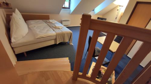 a small bedroom with a bed and a staircase at Hotel Modrásek in Kašperské Hory