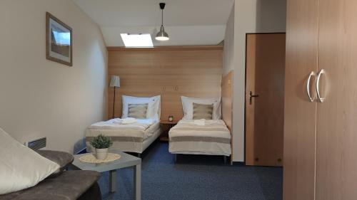 a hotel room with two beds and a couch at Hotel Modrásek in Kašperské Hory